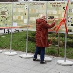 Dwie kobiety przecinają wstęgę na otwarciu wystawy plenerowej.