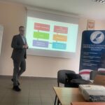 Mężczyzna stoi przy ekranie wyświetlającym schemat.